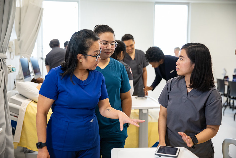 Three nurses talking in a clinical setting