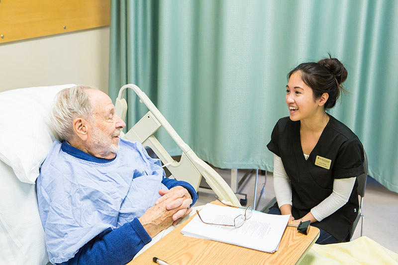 Nurse attending to man in hospital bed