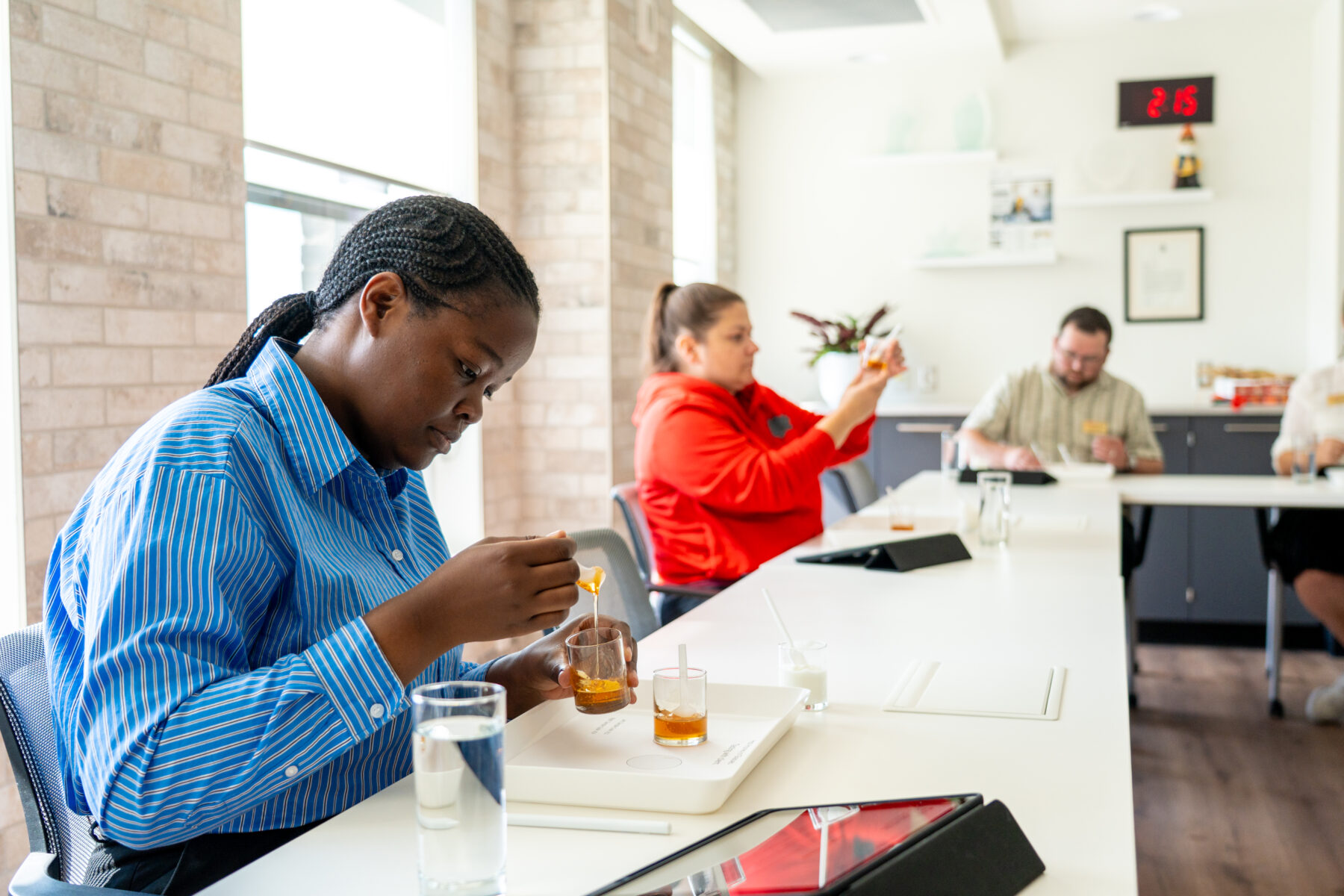 3 people at a table observing and tasting hot honey samples