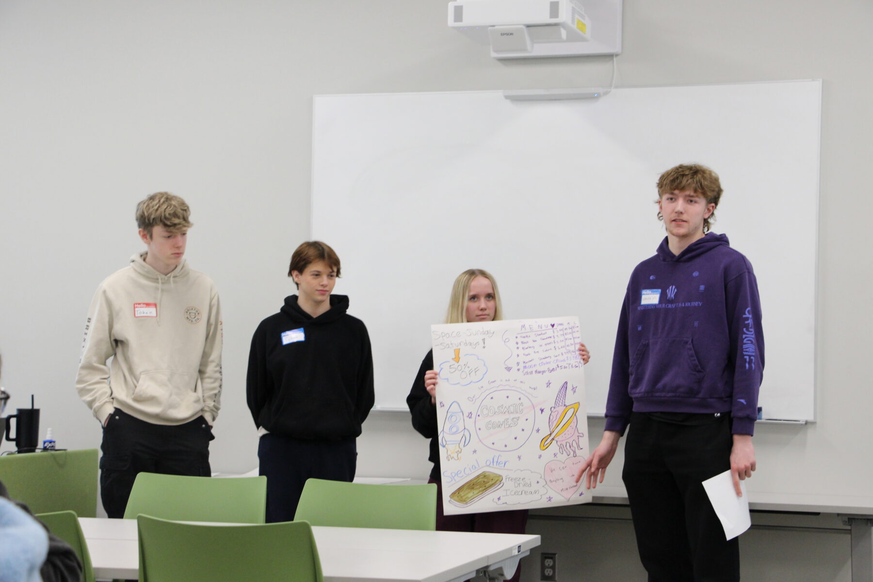 Three students posing for a photo, with one holding up a posterboard
