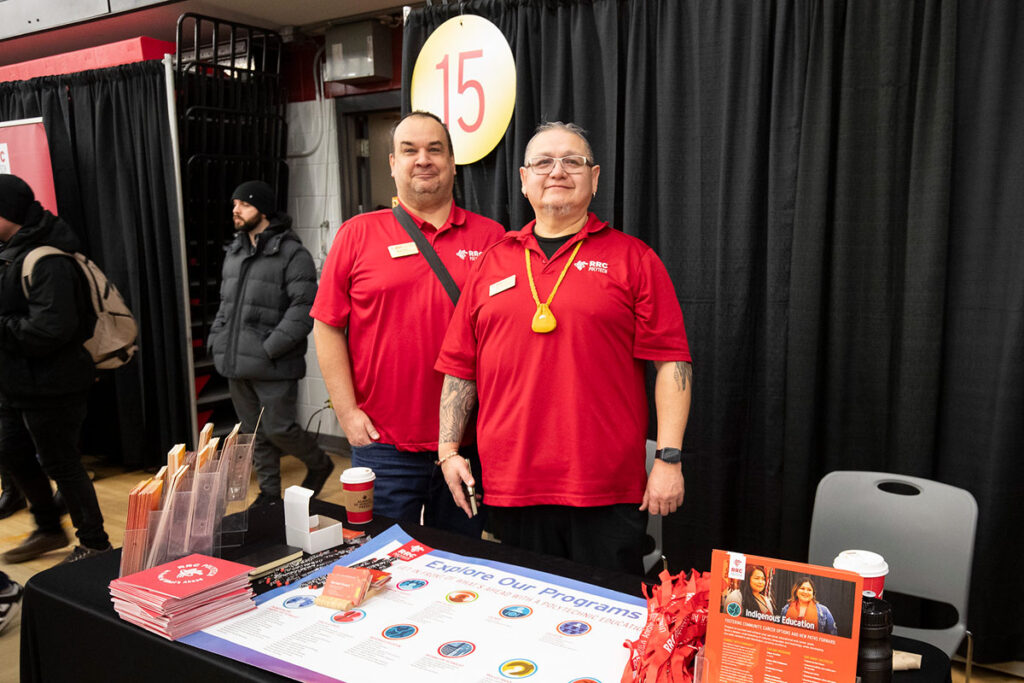 Indigenous student recruiters standing at a booth at a recruitment fair
