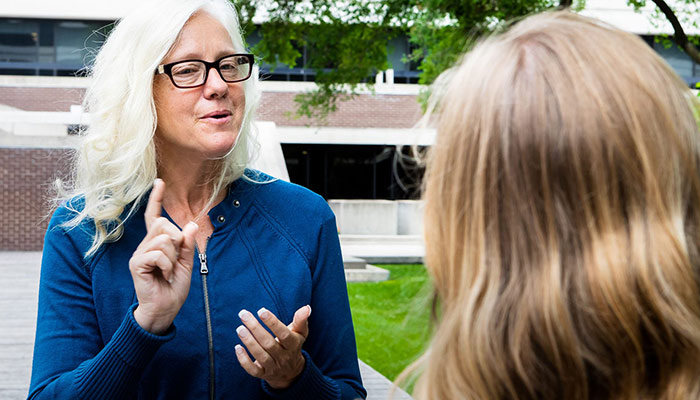 Woman signing to another woman outdoors