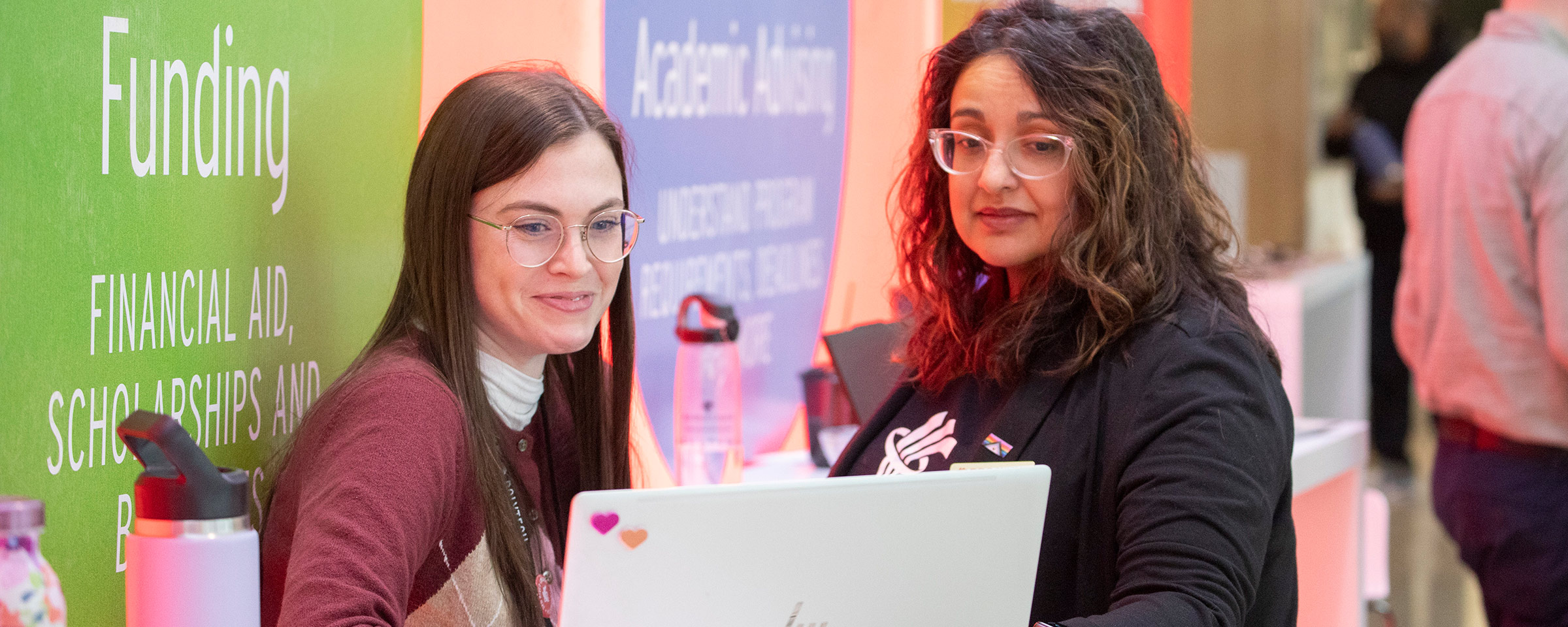 Two people looking at a laptop at a trade show