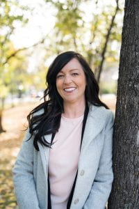 Jaime Manness leaning on tree