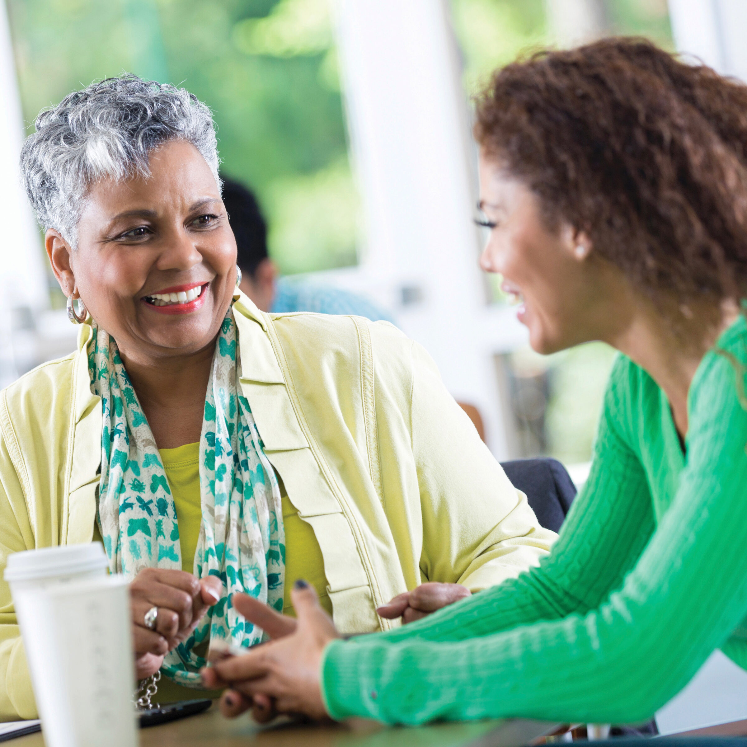 Pleasant businesswoman listening to co-worker at workplace breakroom.