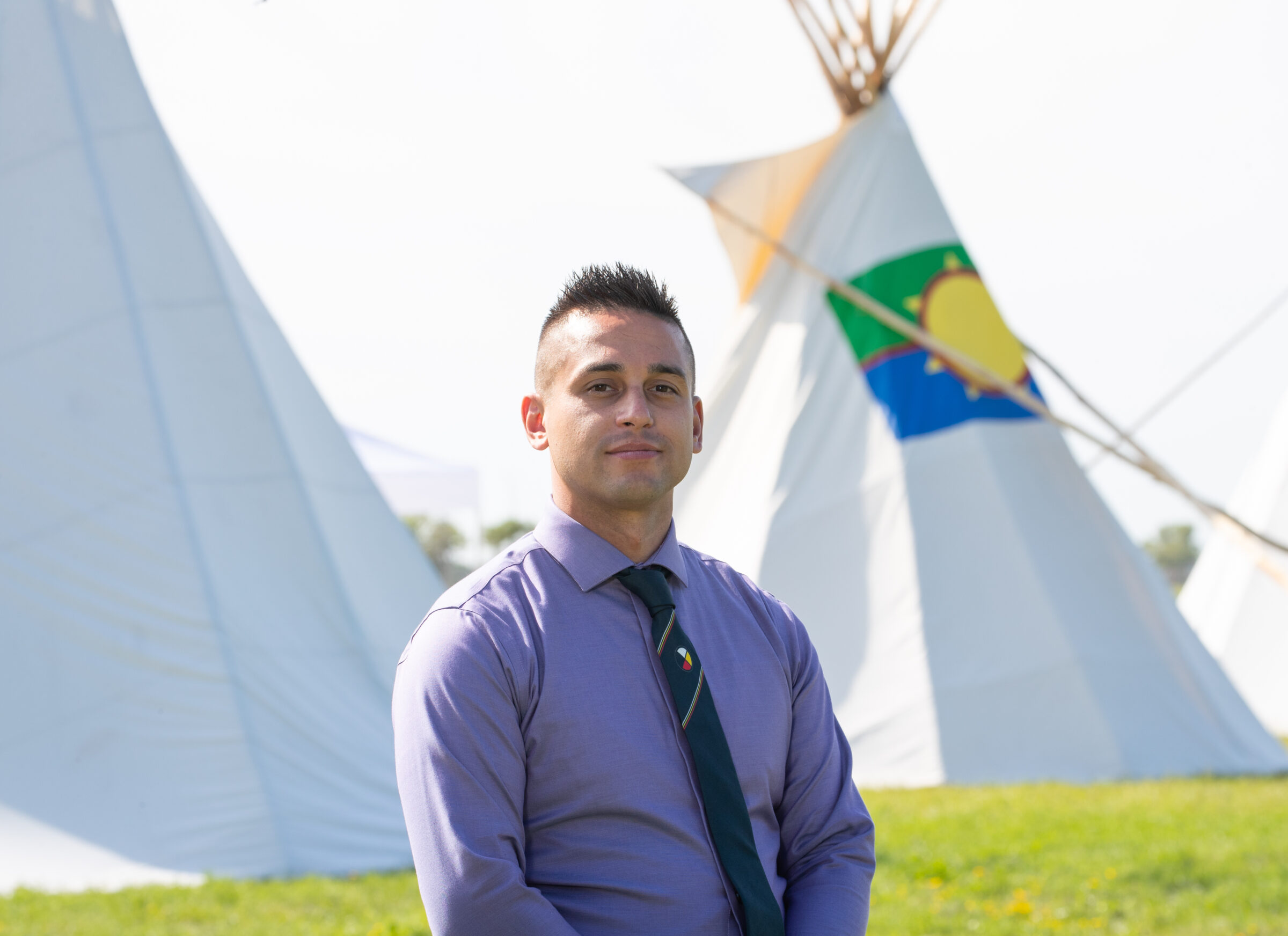 RRC Polytech alumni member Vic Savino in front of two teepees.