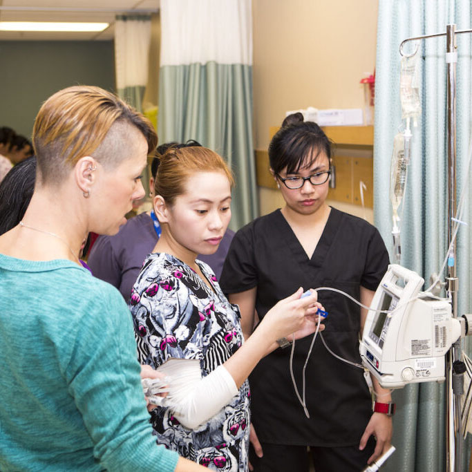 Nursing instructor showing students how to operate a medical device.