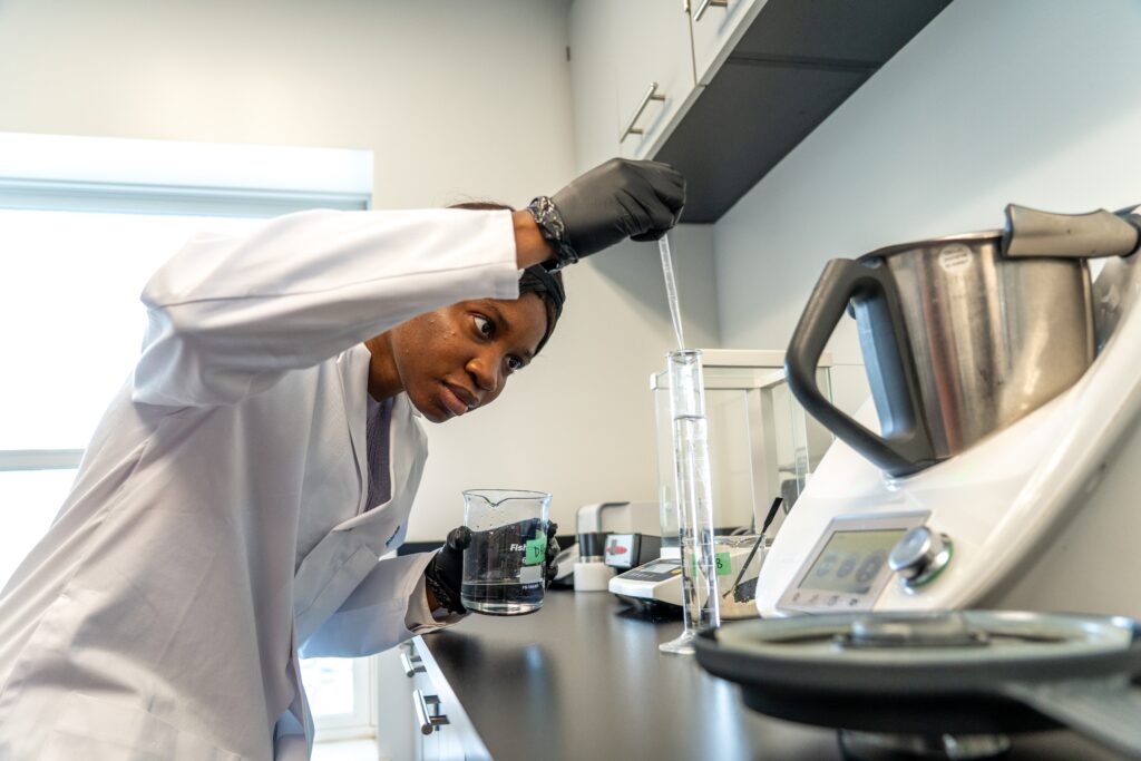 a food scientist in a lab draws liquid from a test tube