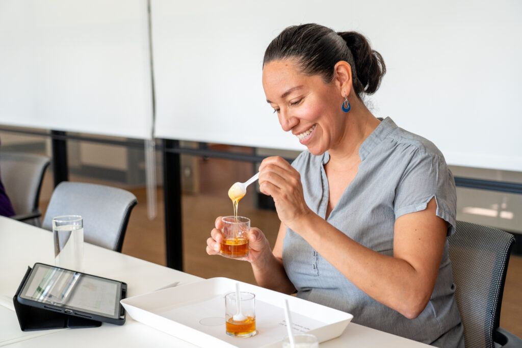 a person transfers hot honey between small glasses with a spoon