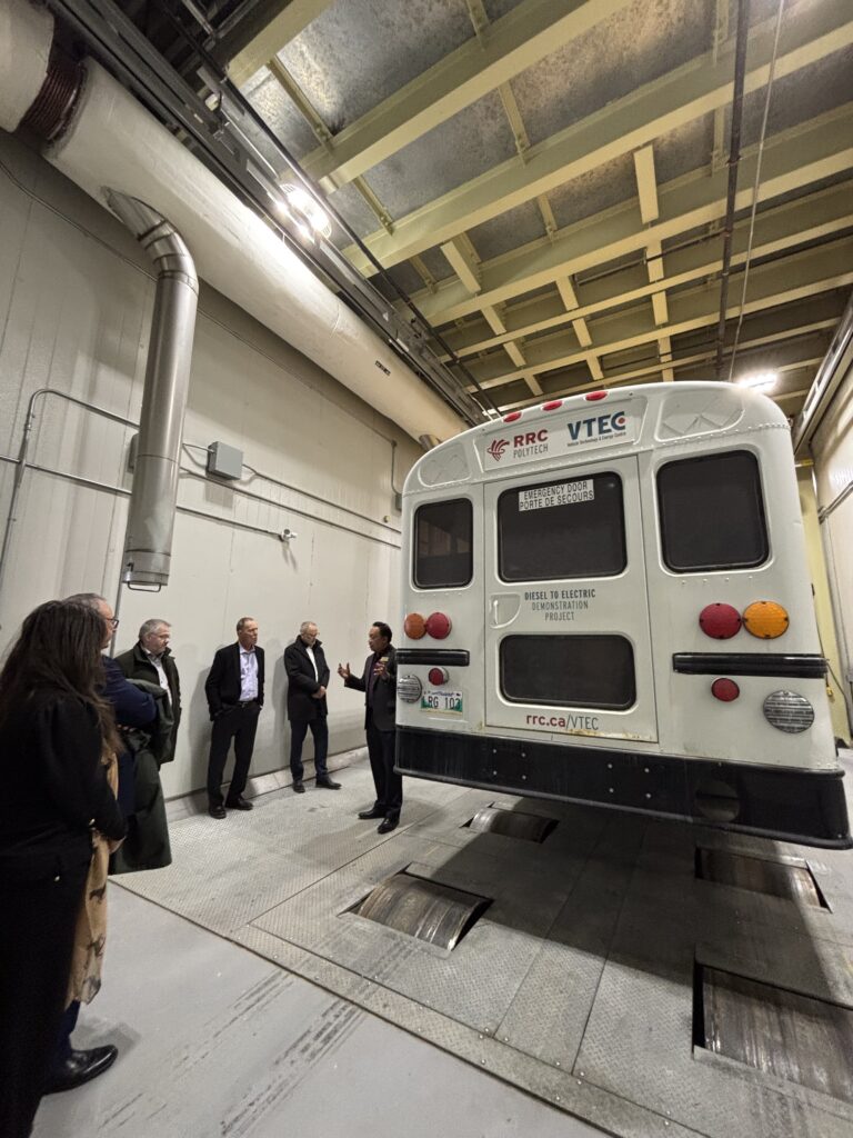 people touring through research areas featuring a bus, a model building, and a robotics lab