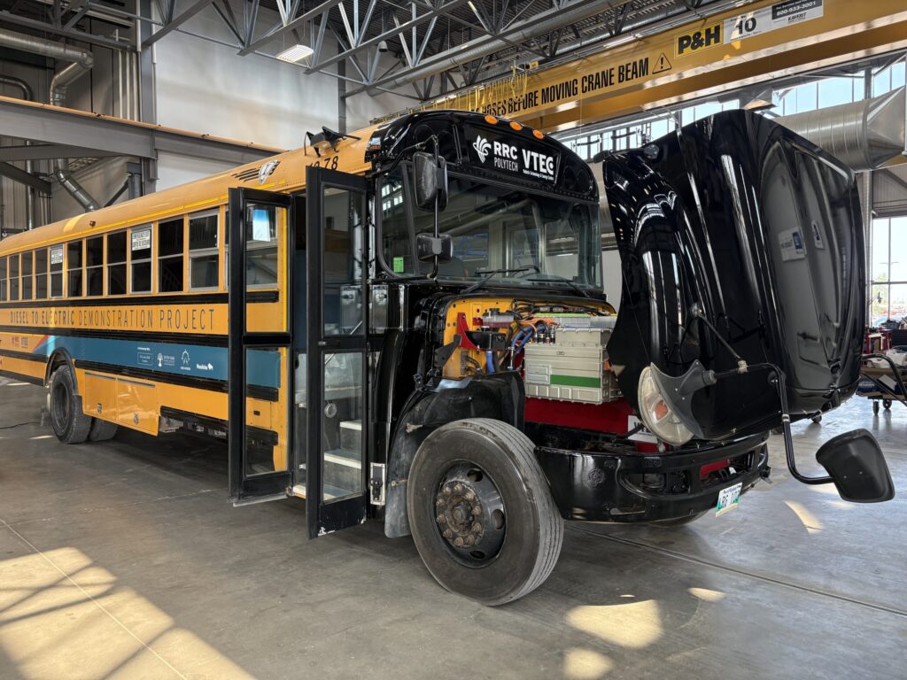 school bus with engine compartment open to show electric motor