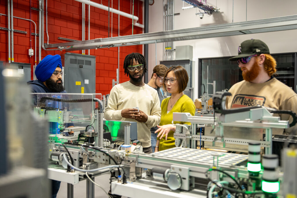 an instructor demonstrates a robotic device with lasers to a group of students