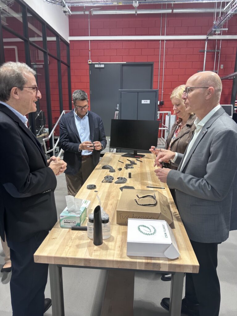 four people talking at a table filled with manufacturing components