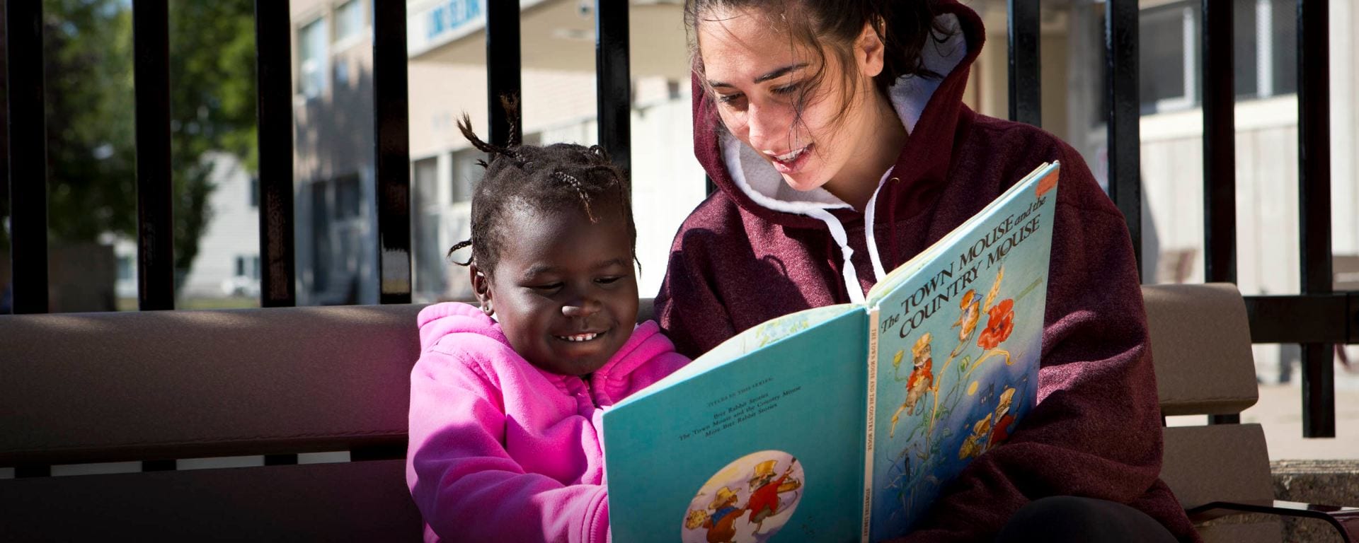 child and adult reading on a bench