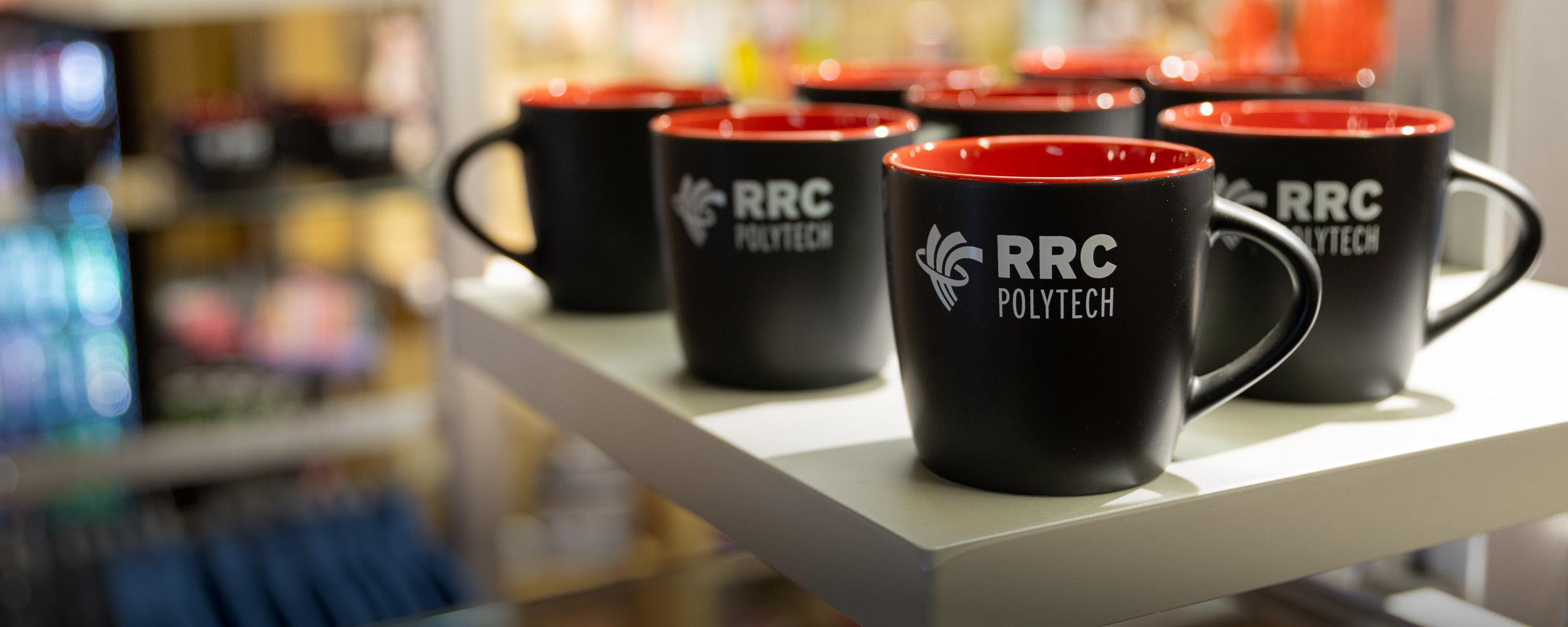 Collection of RRC Polytech coffee mugs on a shelf