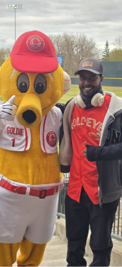 A CNI student posing with the Goldeyes mascot