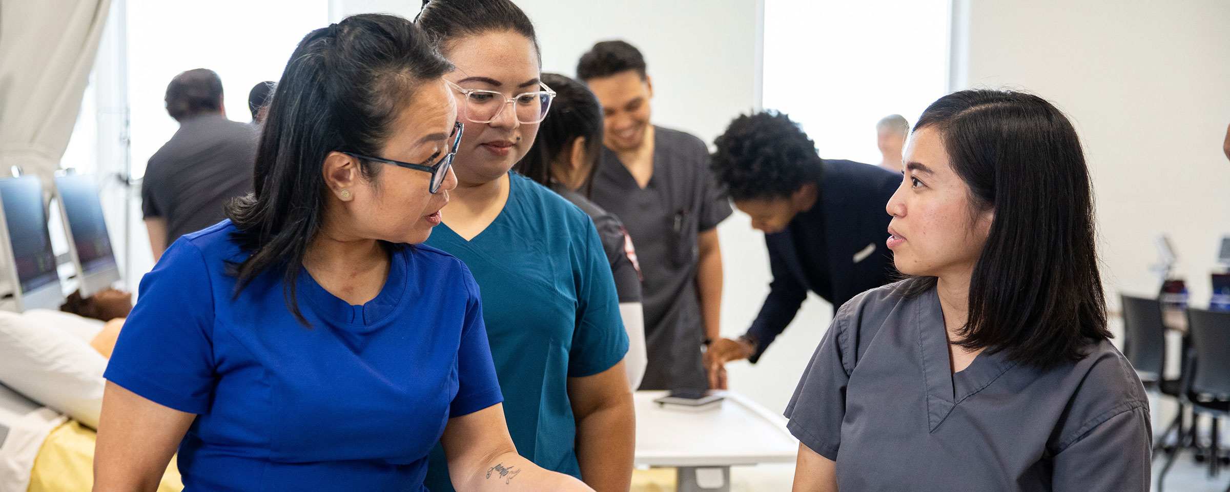 Three nurses talking in a clinical setting