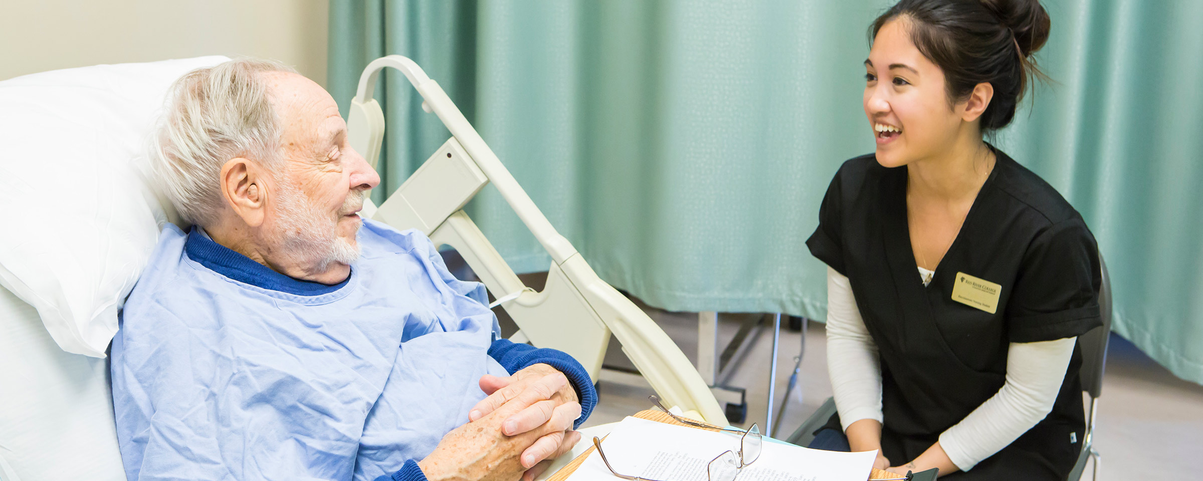 Nurse attending to man in hospital bed