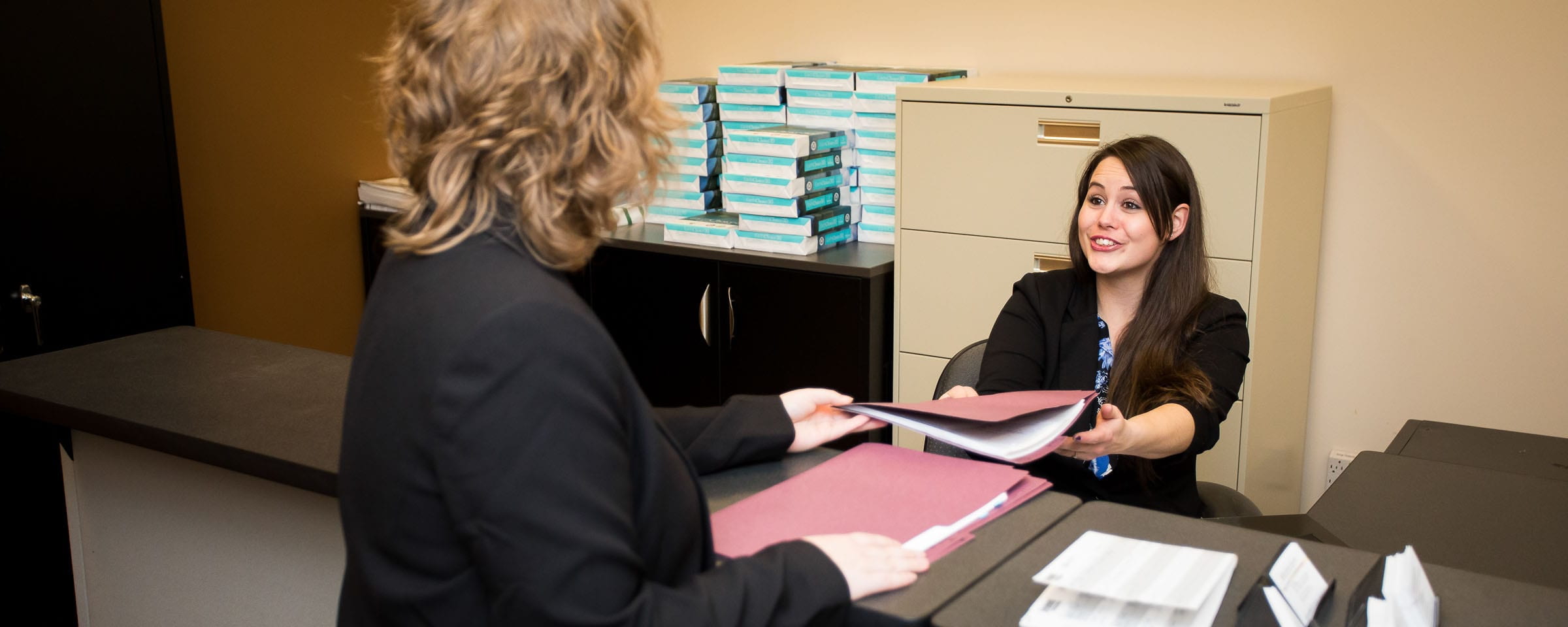 Woman handing folder to another woman