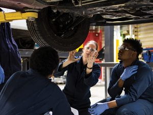 Three people looking under a car