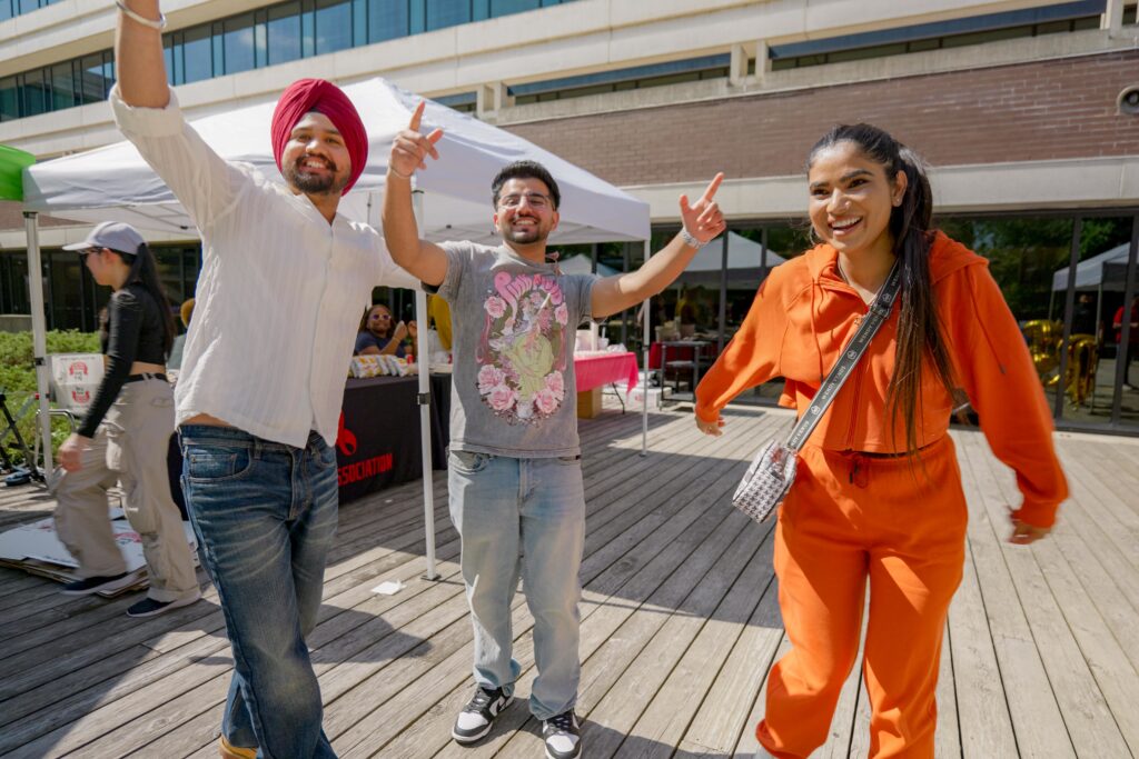 Three people stand together and smile at the camera.