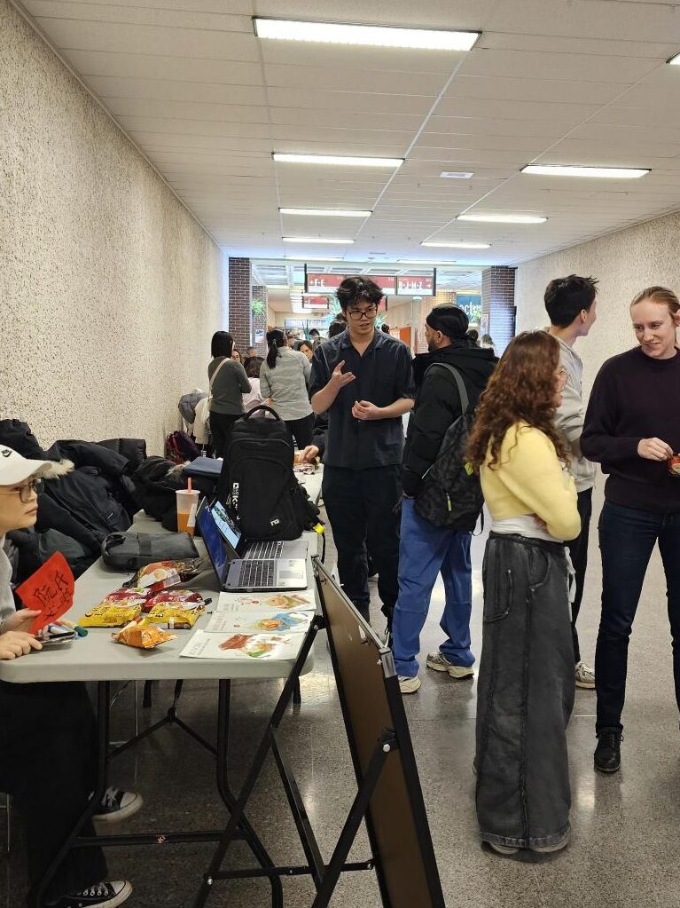 People standing around a table with snacks and cultural materials during an event.