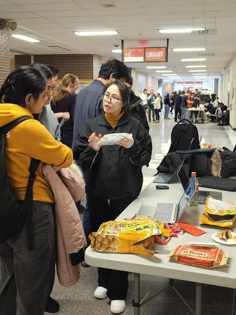 People standing around a table with snacks and cultural materials during an event.
