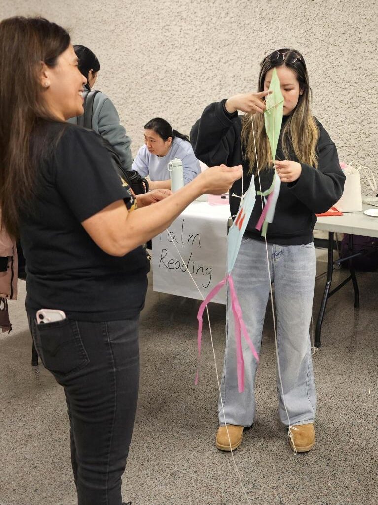 People crafting colorful paper kites together during a campus activity.