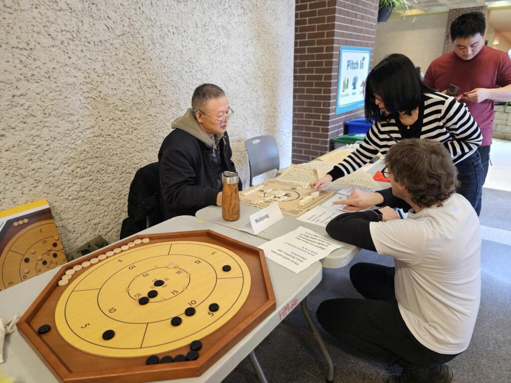 People playing a traditional tabletop game at a booth.