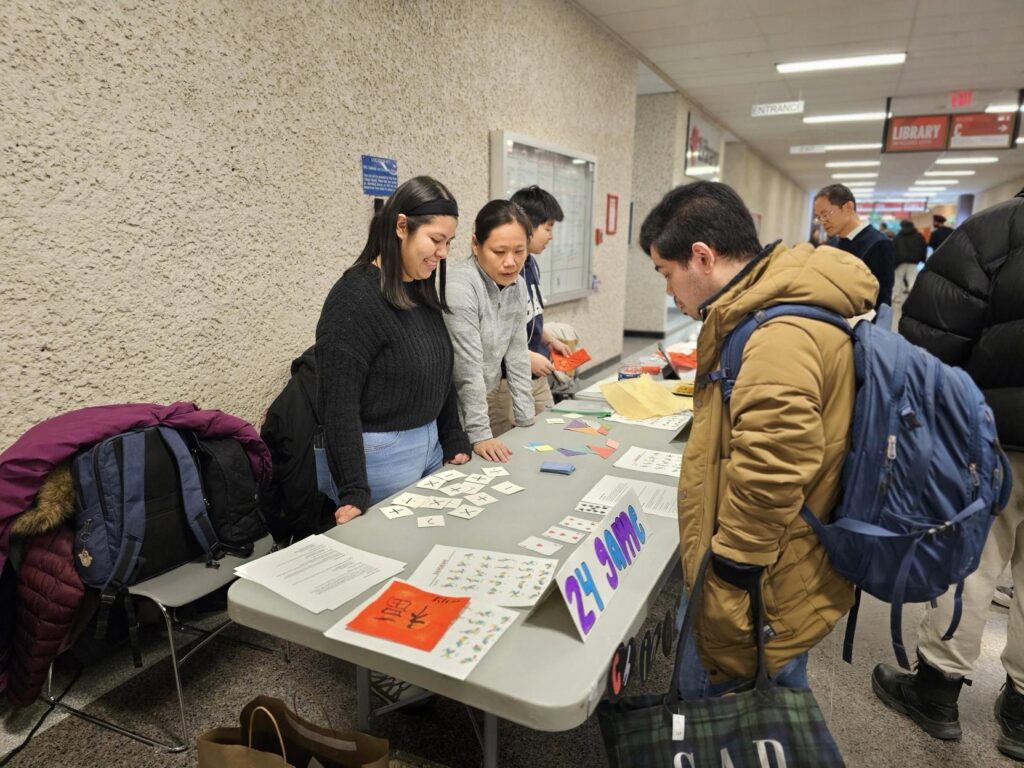 People gathered around a table reviewing cards and learning materials at a campus event.