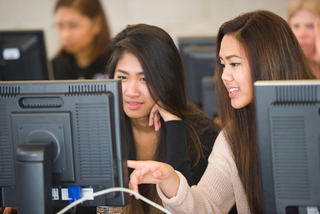Two students working on computers in a computer lab
