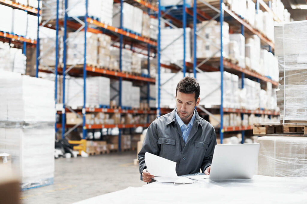Man looking at notes in a large warehouse