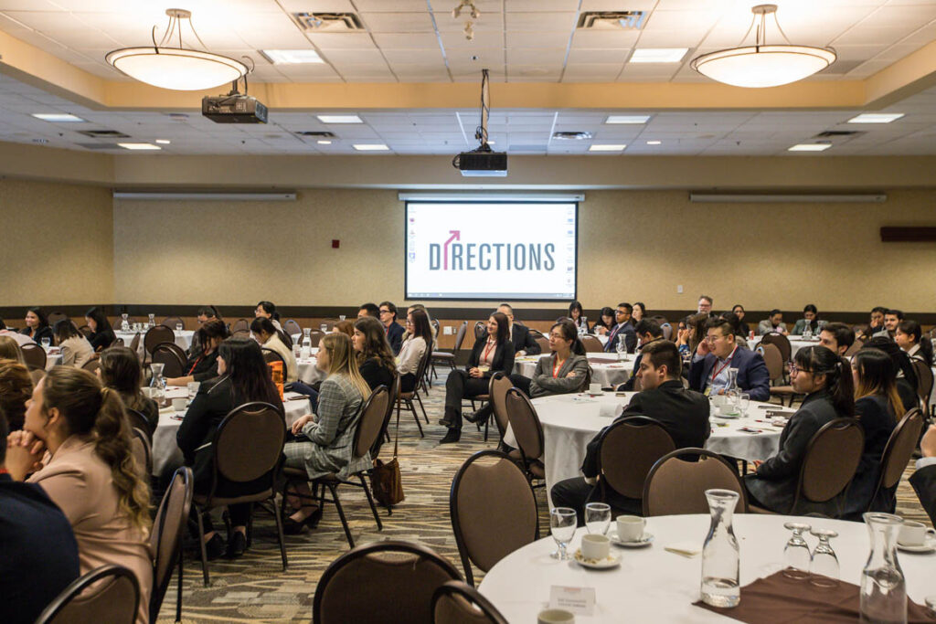 Students sitting around round tables at a conference