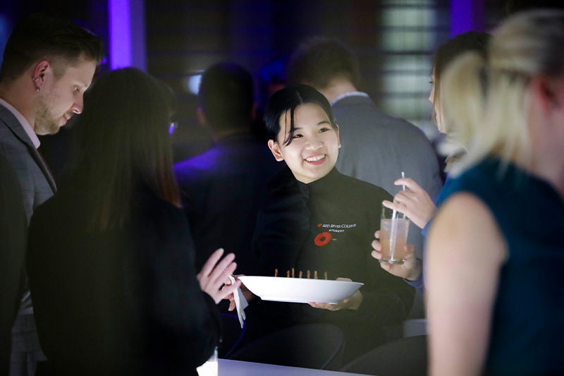 A hostess in a restaurant talking to two guests