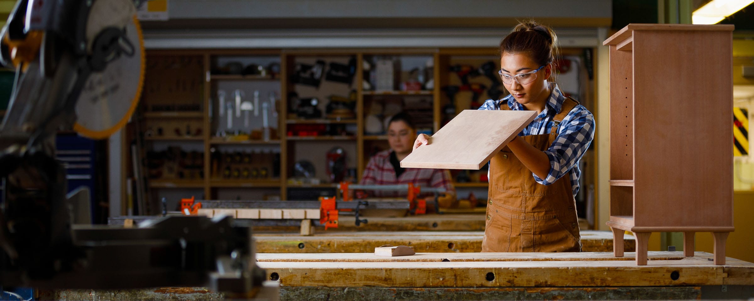 Woman holding piece of wood in a wood shop