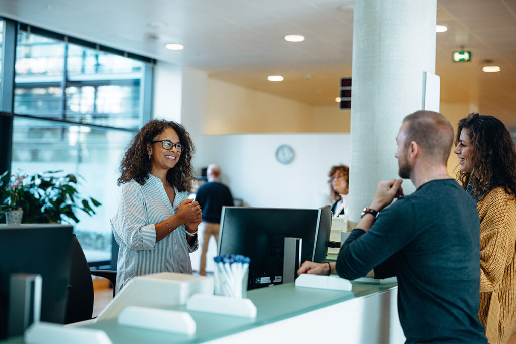 Administrative assistant talking to person at desk in an office