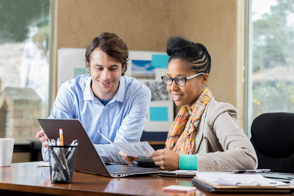 Instructor and student looking at laptop screen in an office