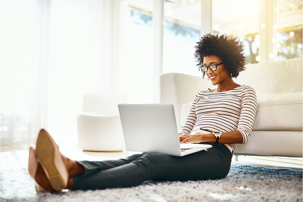 Woman with a laptop sitting on the floor in her living room