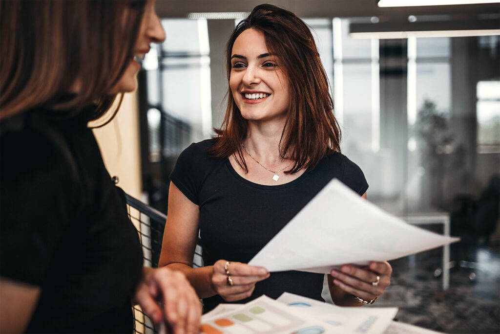 Smiling woman handing notes to another person