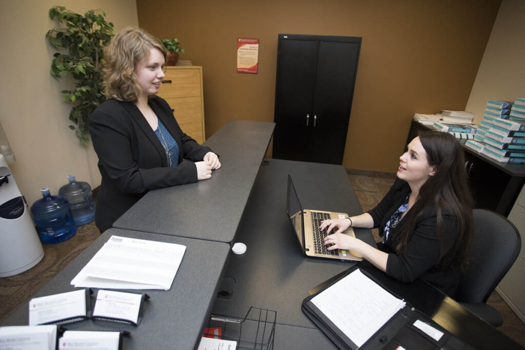 Administrative assistant talking to person at desk in an office