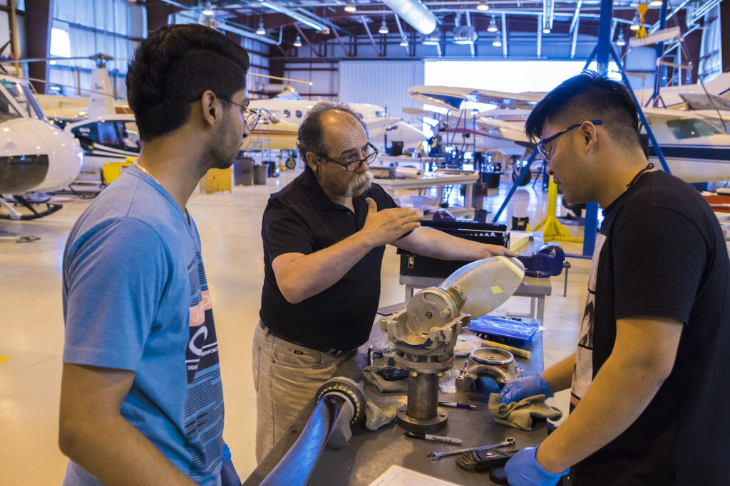 Instructor explaining something to students in an aircraft hangar