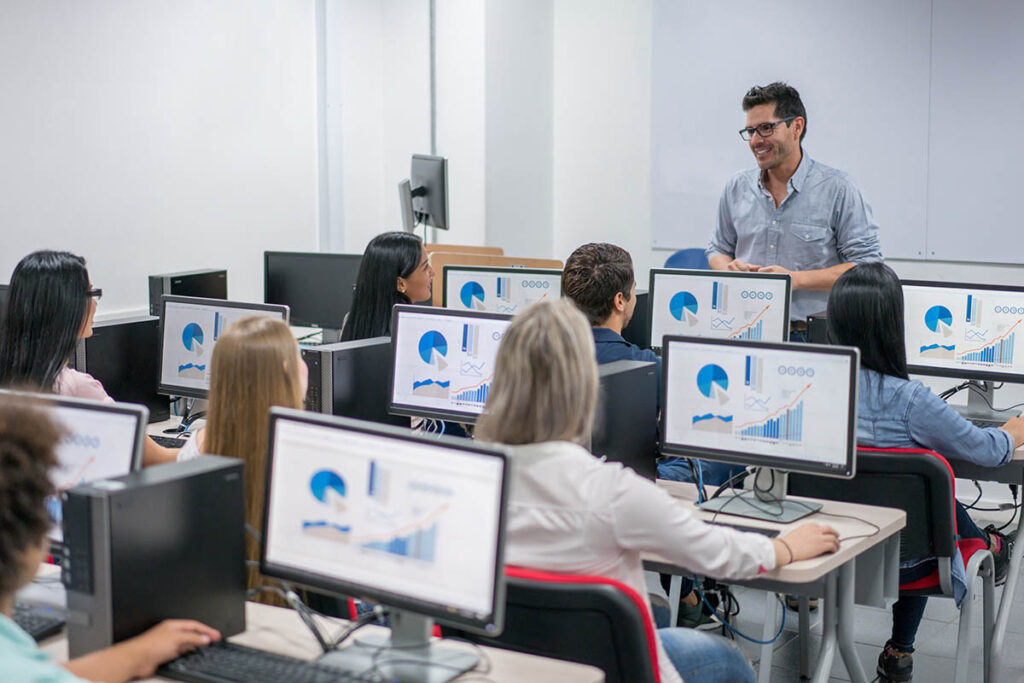 Teacher talking to classroom full of students in a computer lab