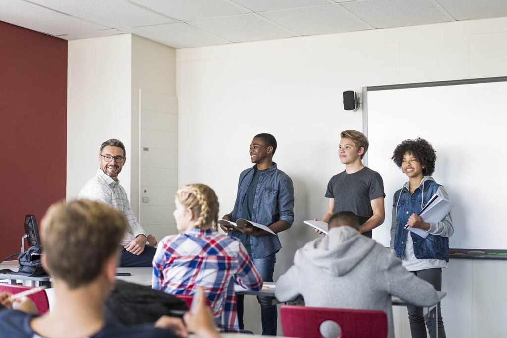 Teacher talking to group of students in a classroom