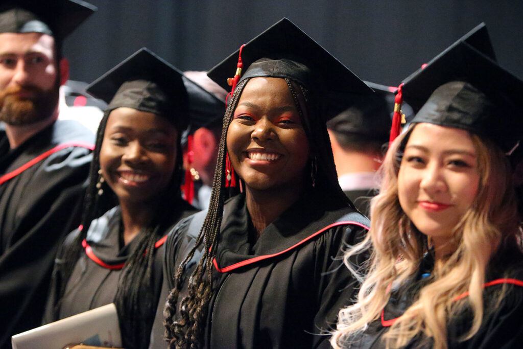 Smiling graduates in convocation gowns at a graduation ceremony