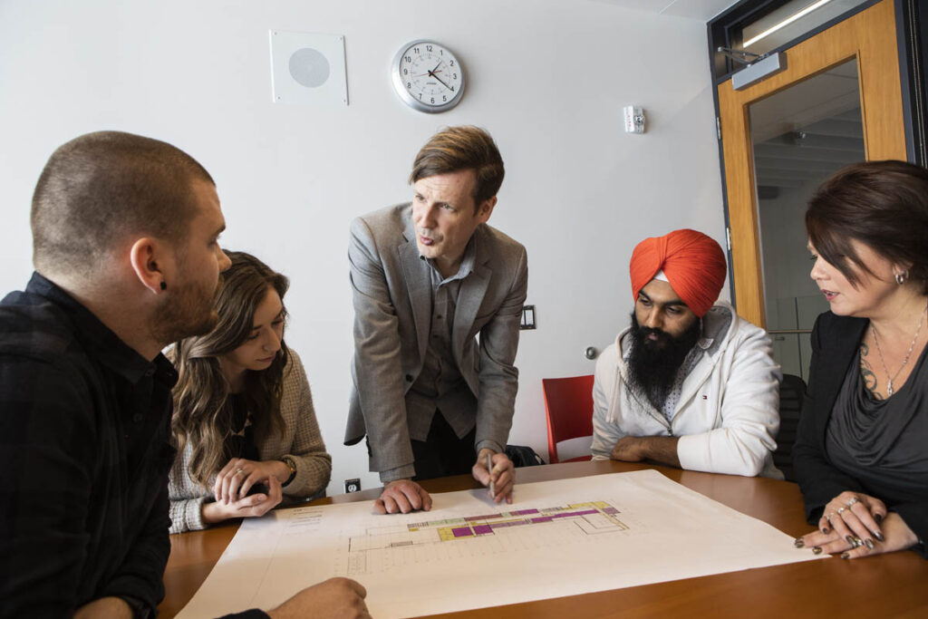 Instructor explaining architectural drawing to students