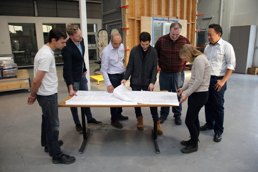 Group of people looking at blueprints on a table in a lab