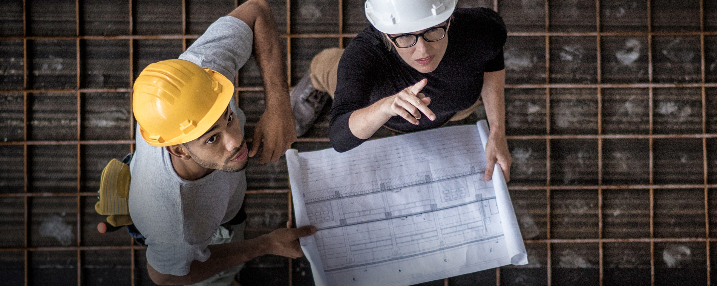 Birdseye view of two engineers looking at blueprints at a construction site