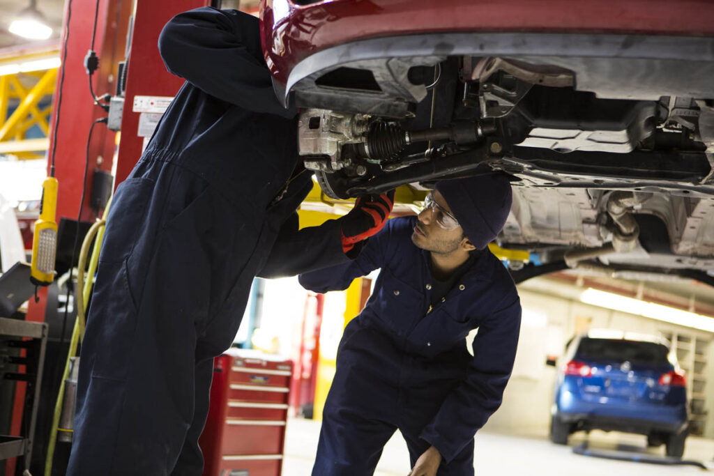 Two automotive students working on a vehicle in a shop