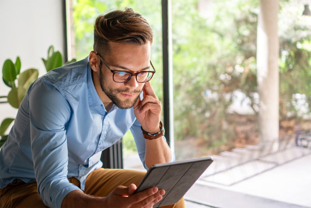 Man in business attire looking at a tablet in his house 