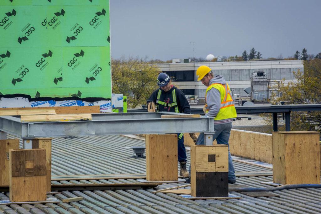 Two construction workers at a job site building a metal frame